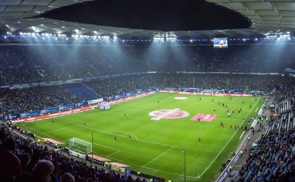 Fans verfolgen ein Flutlichtspiel im vollbesetzten Stadion